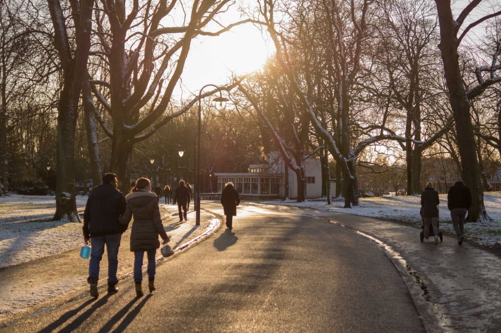 People strolling in a snow-covered park during sunset, creating serene winter vibes.
