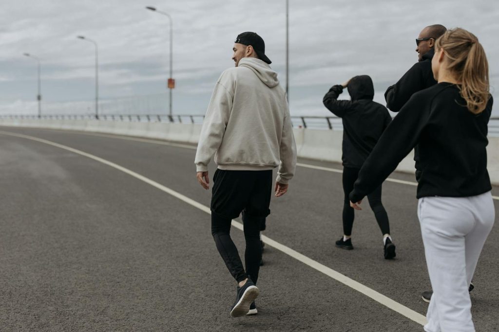 A group of four adults walking for exercise on a city road during a cloudy day.