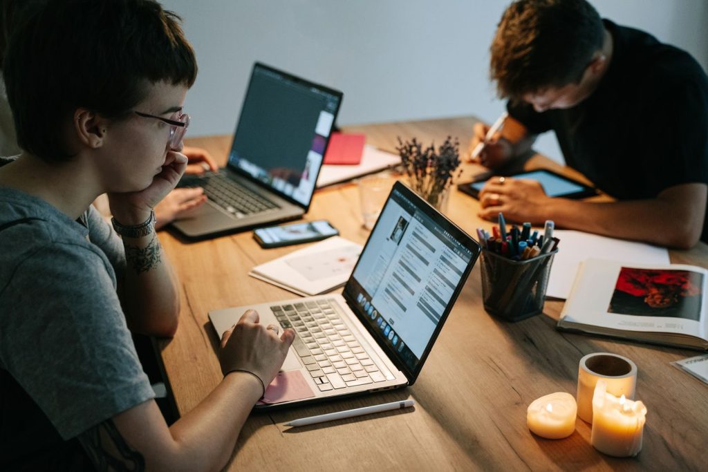 Two young professionals collaborating in a cozy office with laptops, notebooks, and candles.