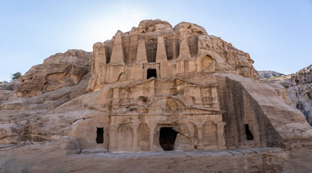 Explore this majestic ancient rock-cut temple nestled in a mountainous landscape, a marvel of historical architecture.