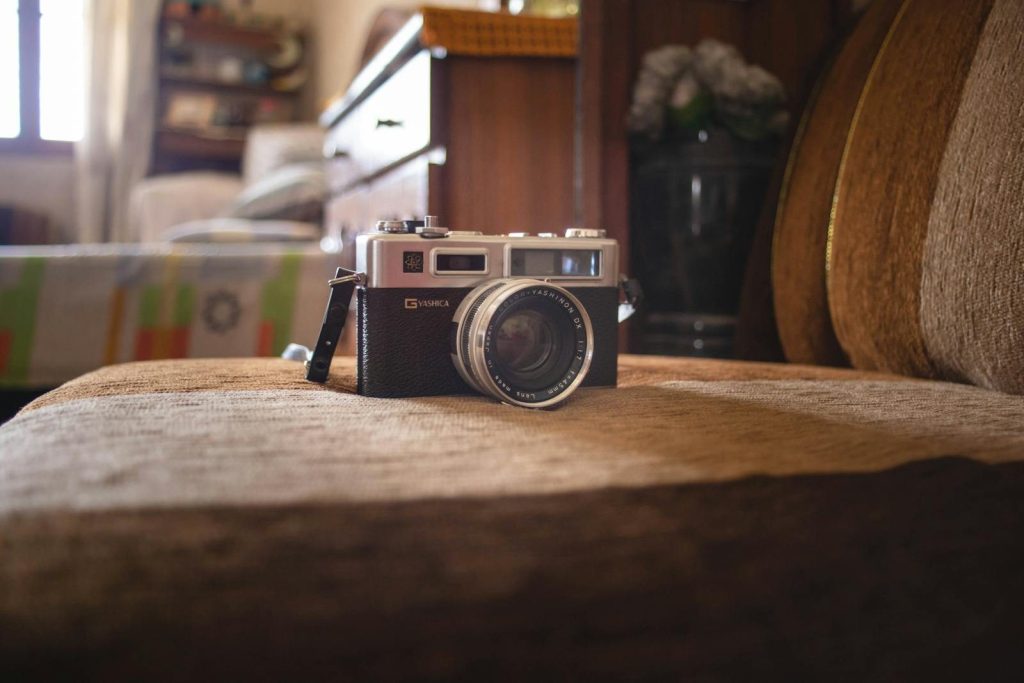 Close-up of a vintage camera on a brown sofa, indoor cozy atmosphere.