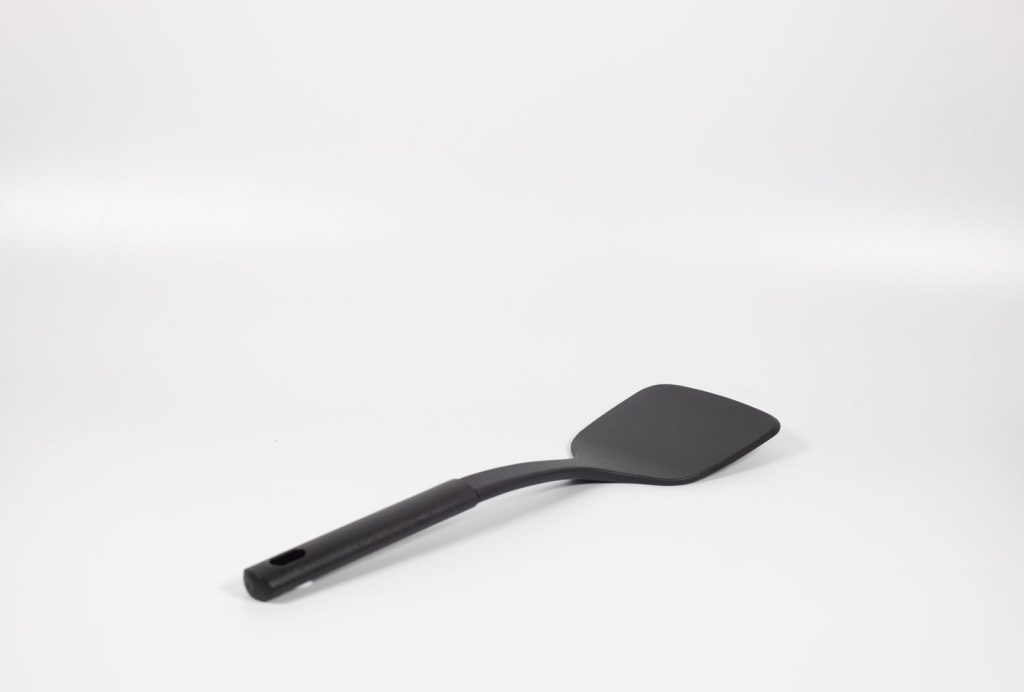 Minimalist photo of a black spatula on a white background, showcasing its utility.