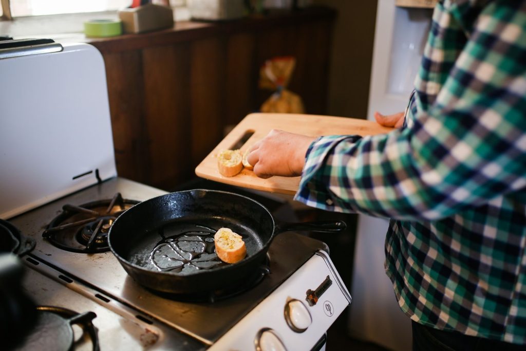 Person cooking with skillet on stove, preparing a delicious meal. Cozy kitchen atmosphere.
