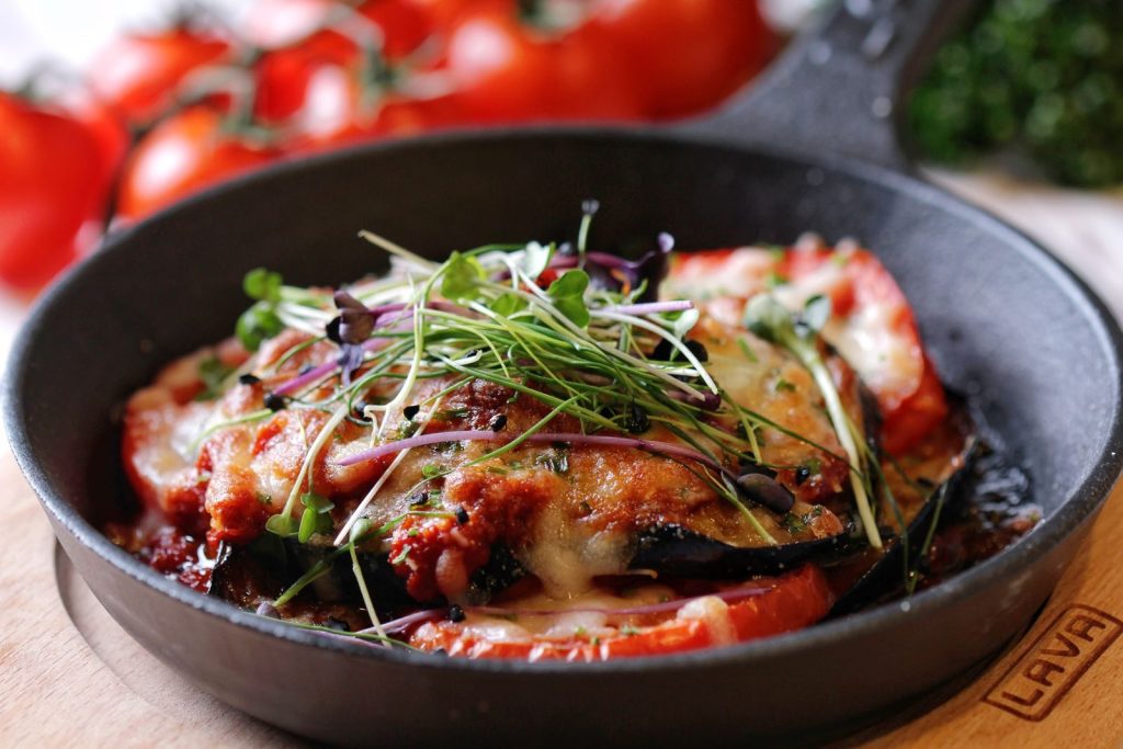 Mouth-watering vegetable and cheese dish garnished with fresh herbs in a skillet.