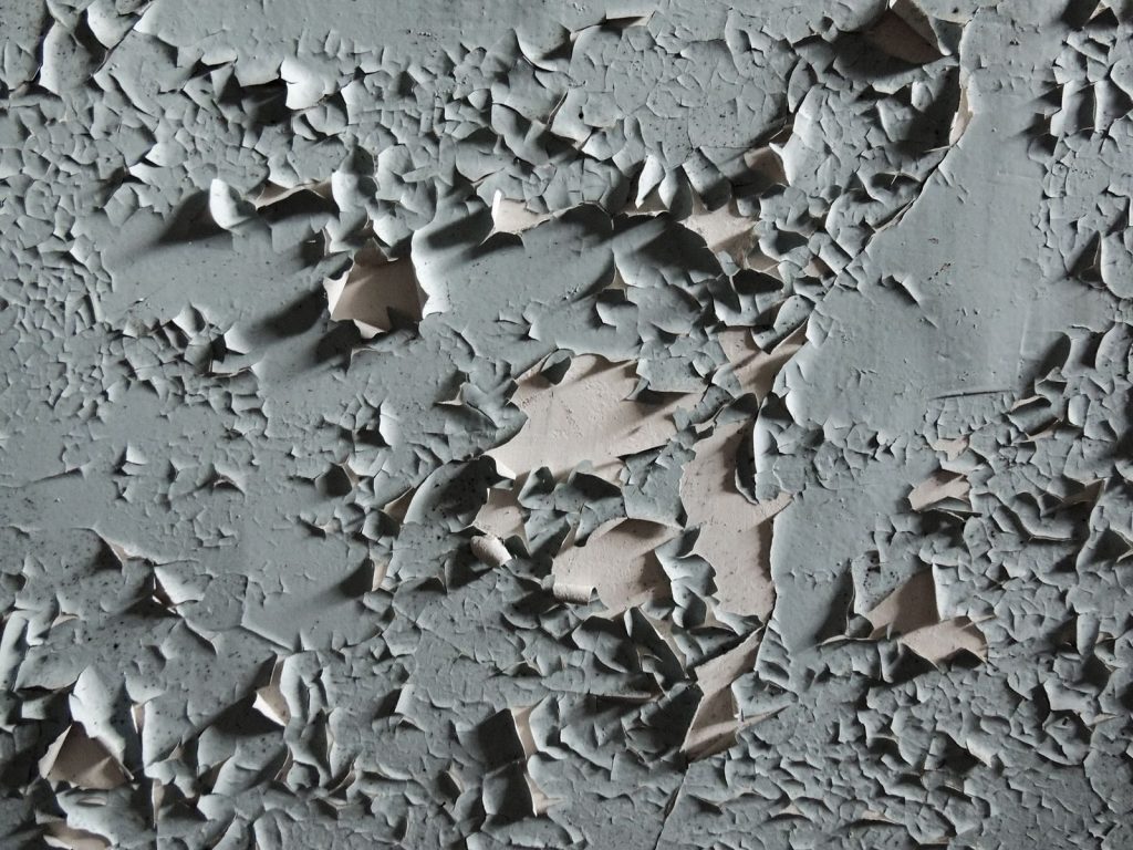 Detailed texture of cracked and peeling paint on an aged wall surface.