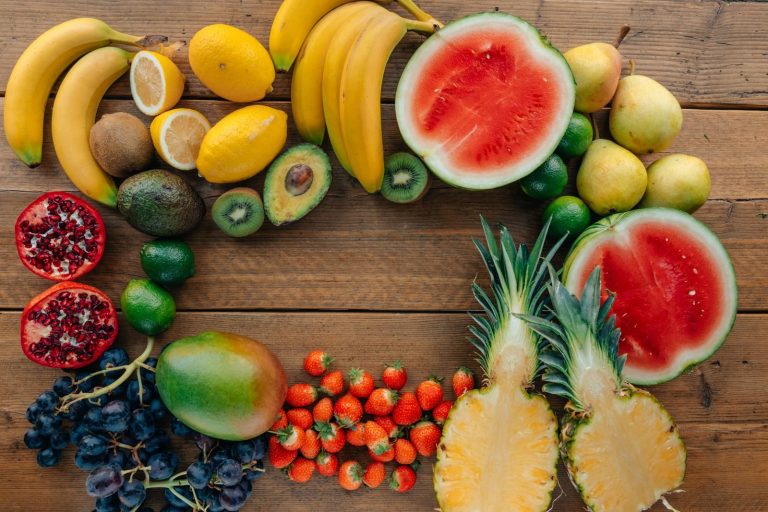 Colorful assortment of fresh fruits in a flatlay on wooden surface, perfect for healthy lifestyle themes.