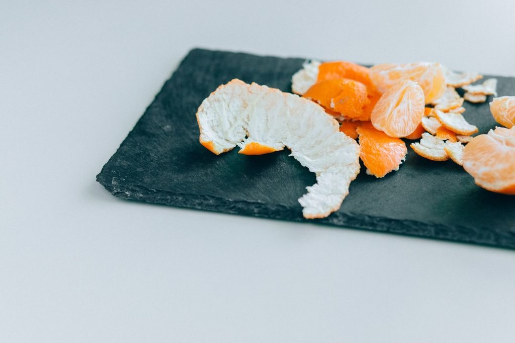Close-up of peeled mandarins on a dark slate board, displaying freshness and vibrant color.