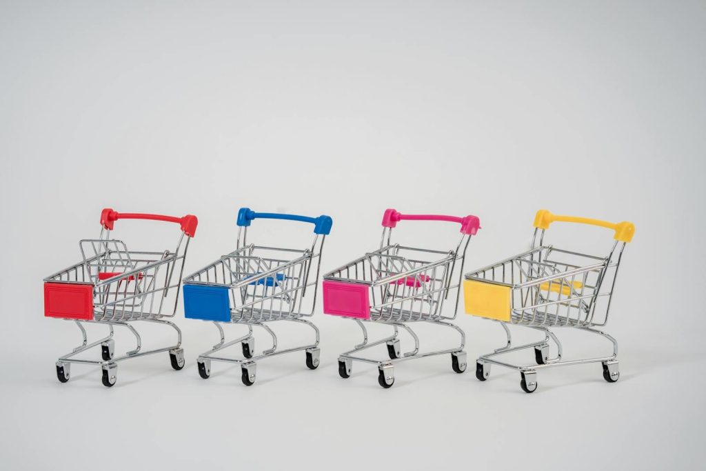 A row of colorful miniature shopping carts arranged against a neutral background.