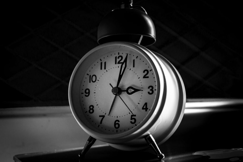 A close-up of a vintage analogue alarm clock in elegant monochrome style.