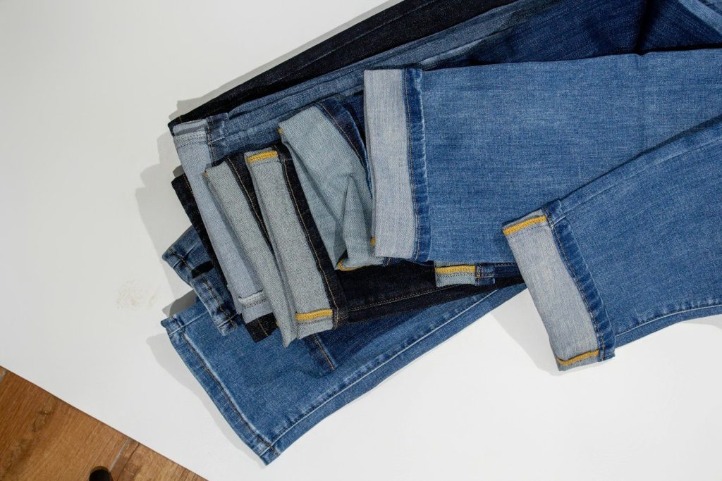 a pile of jeans sitting on top of a wooden floor