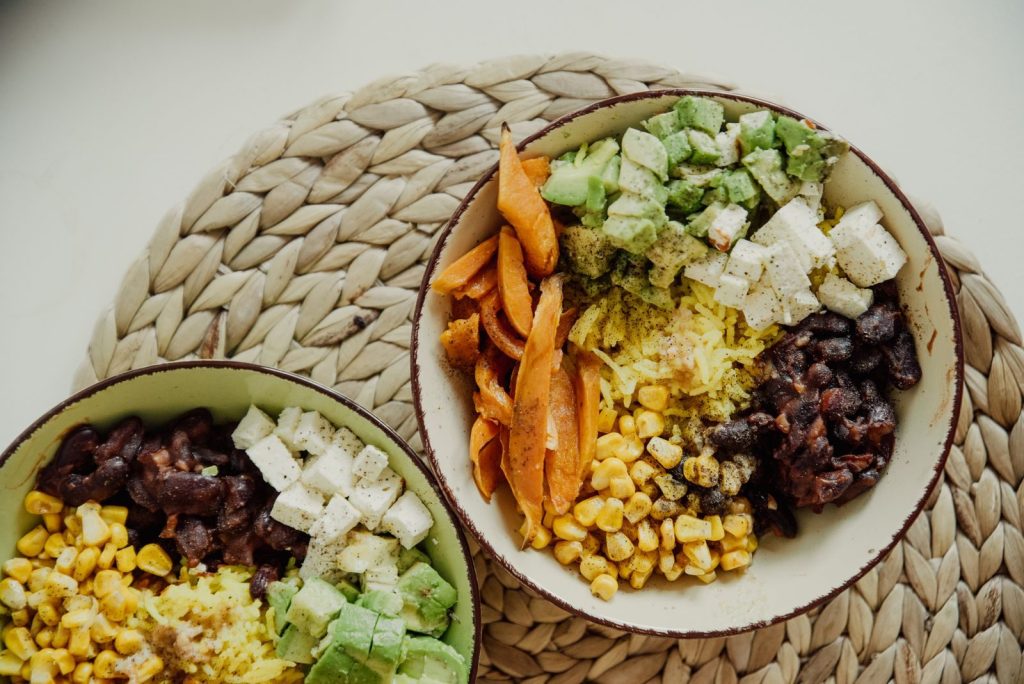 Top view of vegetarian bowls with avocado, corn, beans, and cheese for a delicious meal.