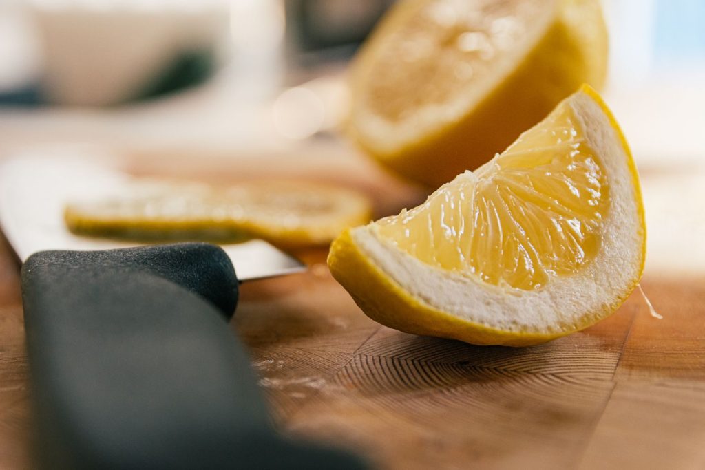 A vibrant close-up of freshly sliced lemons on a wooden cutting board with a knife nearby.