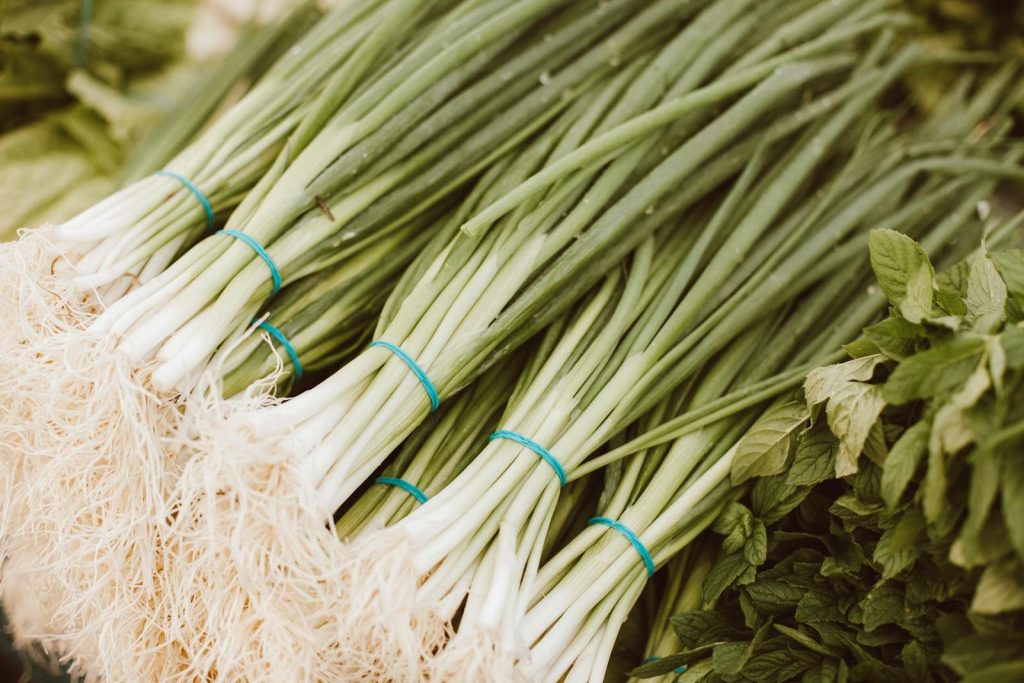 Close-up view of bundles of fresh scallions and herbs ready for sale at a farmers market.