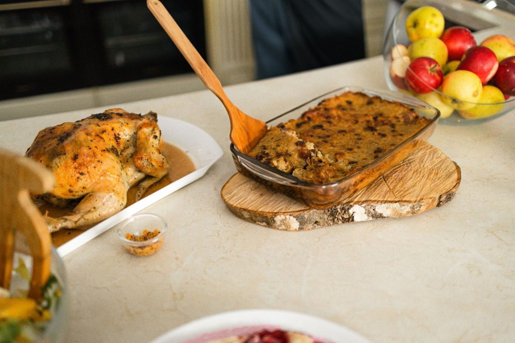 Appetizing roasted chicken served with homemade stuffing and fresh fruits on a table.
