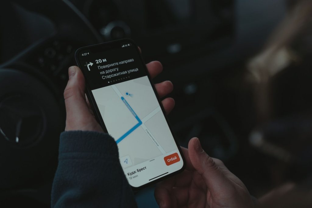 Close-up of a smartphone displaying a navigation app in a car, highlighting modern technology use while driving.