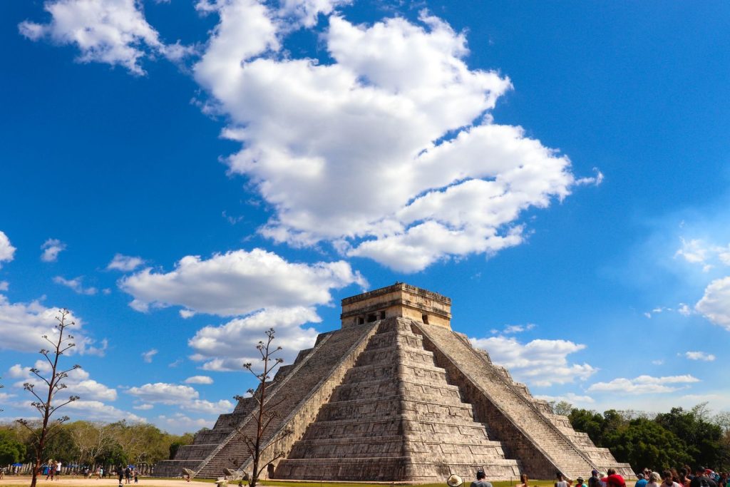 Stunning view of the Chichen Itza pyramid in Mexico with a bright blue sky and fluffy clouds.