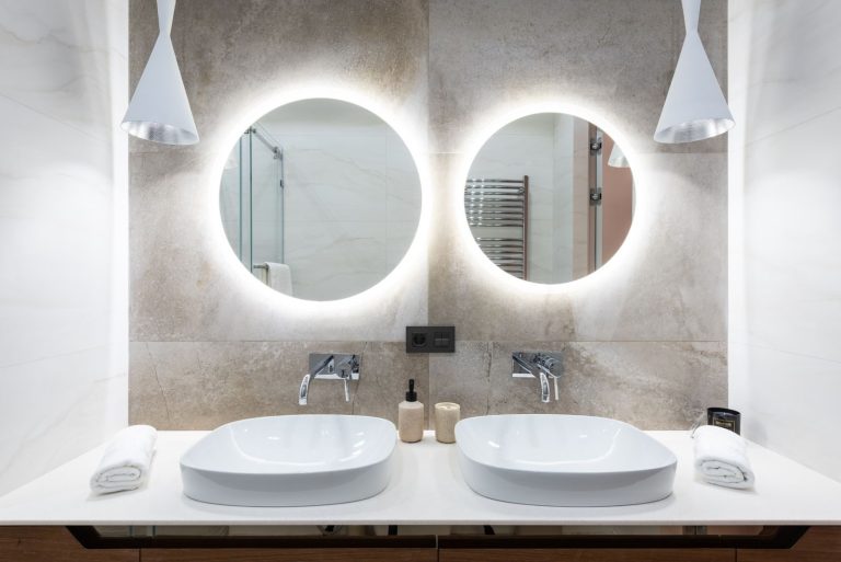 Interior of light modern bathroom with round mirrors near lamp hanging from ceiling and white sinks