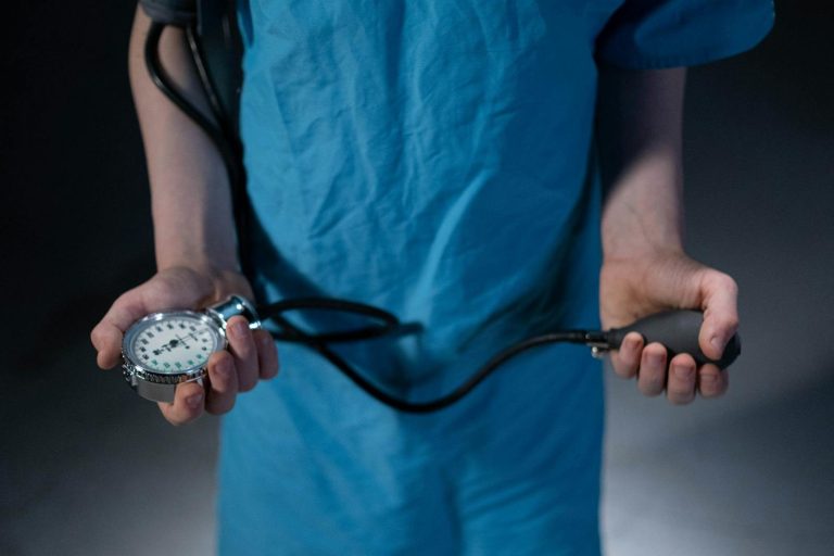 Healthcare professional holding a sphygmomanometer, highlighting medical care and examination tools.