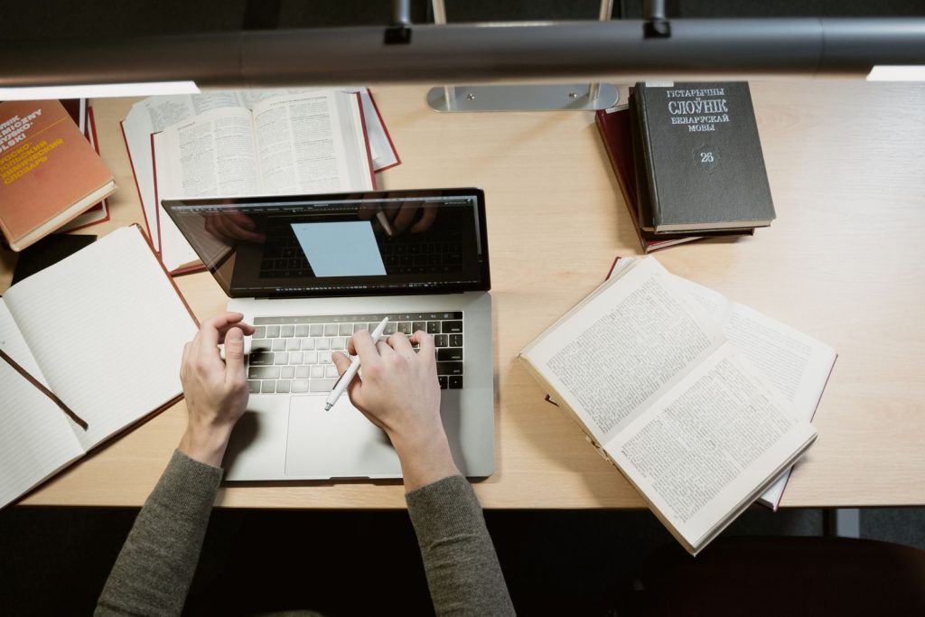 A student studies with a laptop and books, showcasing a learning environment.