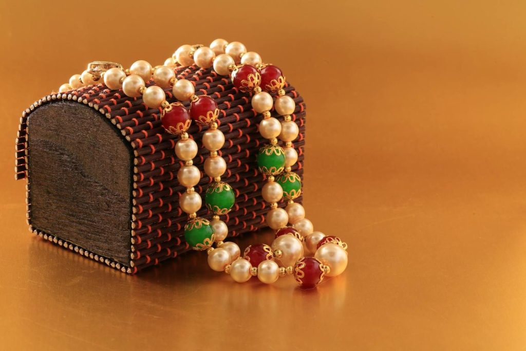 Close-up of a pearl necklace draped over an ornate wooden box, ideal for gifting.