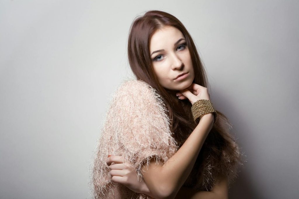Portrait of a stylish young woman posing with a fashionable outfit, featuring a textured top and bracelet.