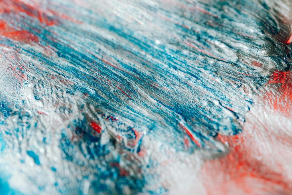 Close-up of abstract acrylic paint art with vibrant blue and red brushstrokes.
