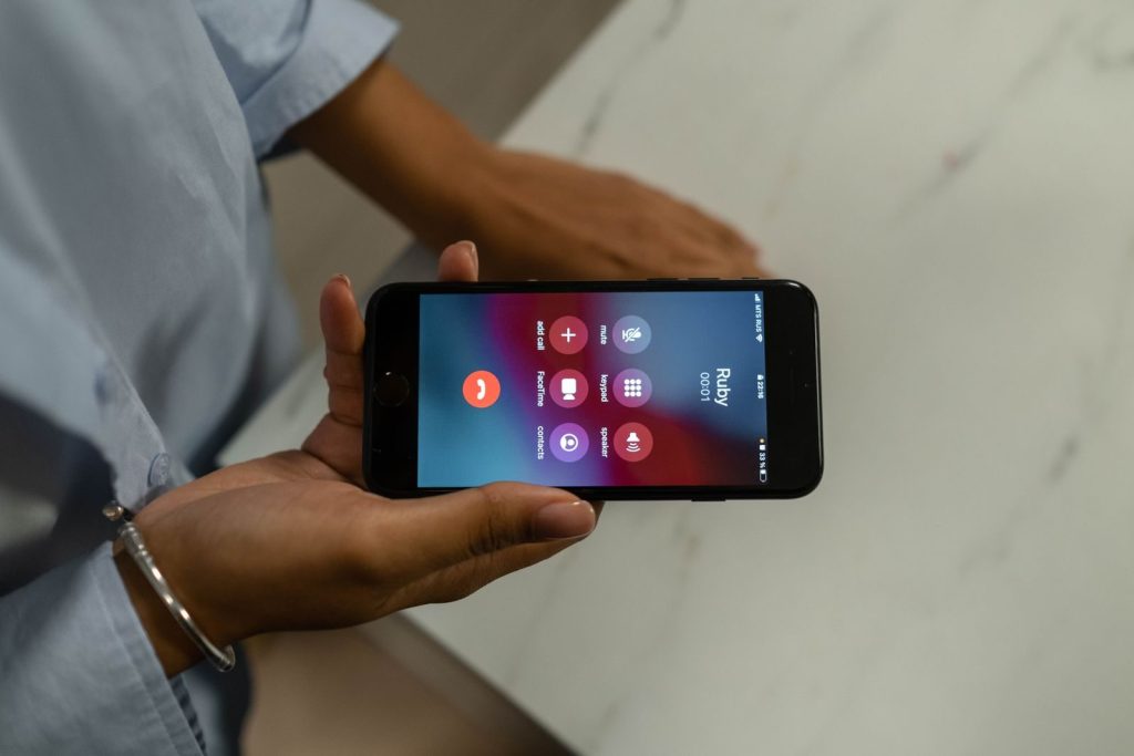 Close-up of a person holding a smartphone displaying an incoming call screen.