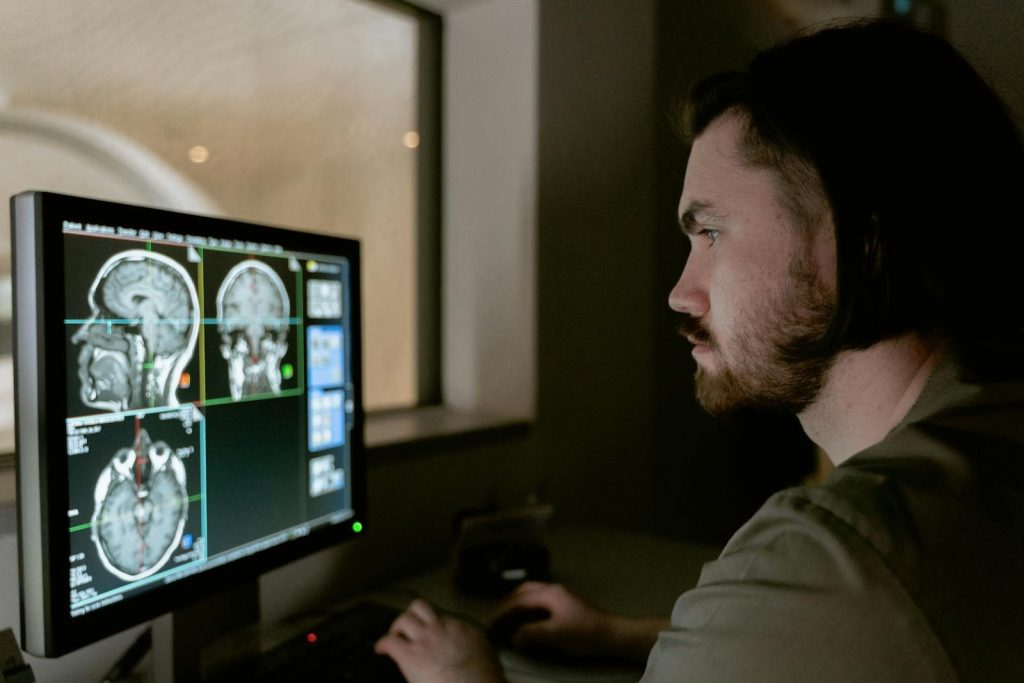 Radiologist examining a CT scan on a monitor in a medical facility.