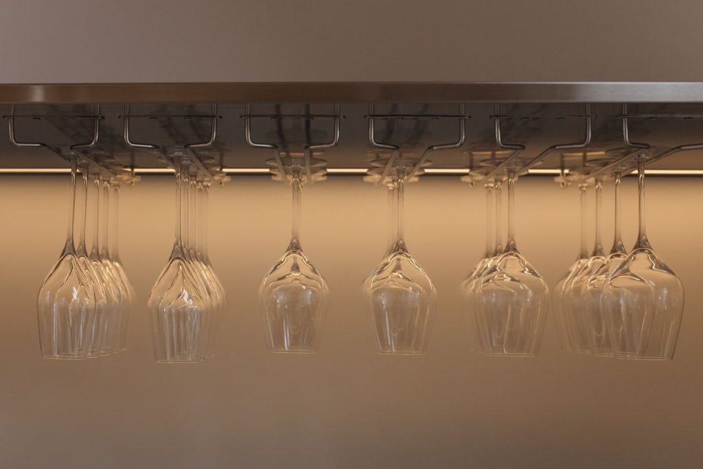 Upside-down hanging wine glasses on a stainless steel rack, perfect for elegant bar settings.