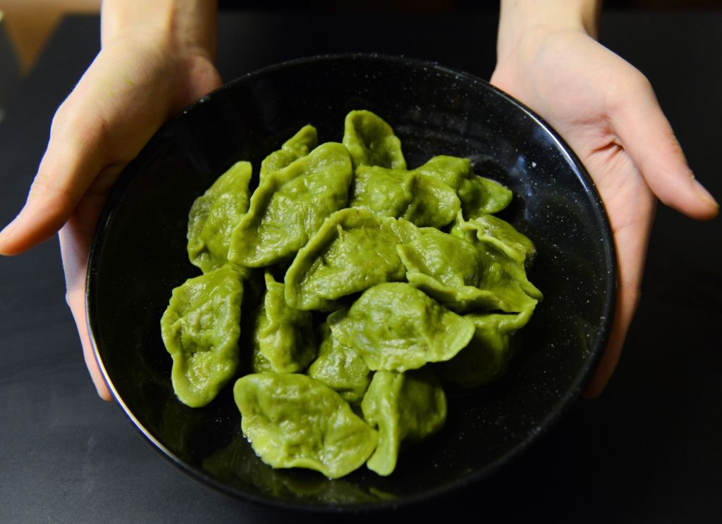 A close-up of fresh green spinach dumplings served in a black bowl, perfect for healthy dining.