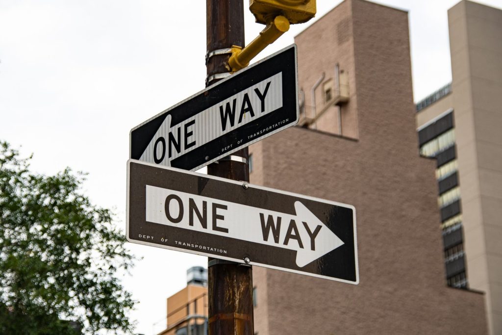 Close-up of one way street signs in urban New York City setting.