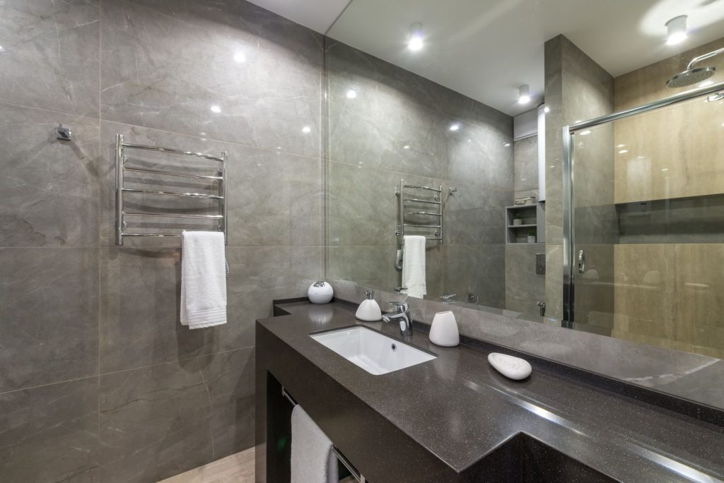 Spacious modern bathroom featuring granite countertop, glass shower, and stainless steel fixtures.