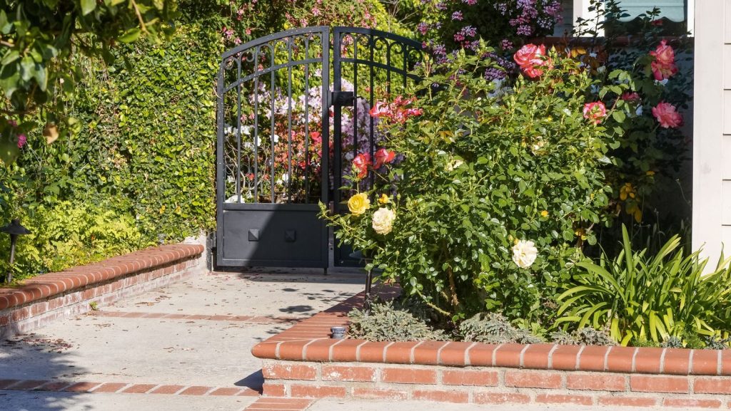 A delightful garden featuring vibrant roses and an elegant iron gate, perfect for residential appeal.