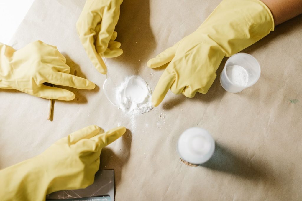A top view of hands in latex gloves conducting a powder experiment on brown paper.