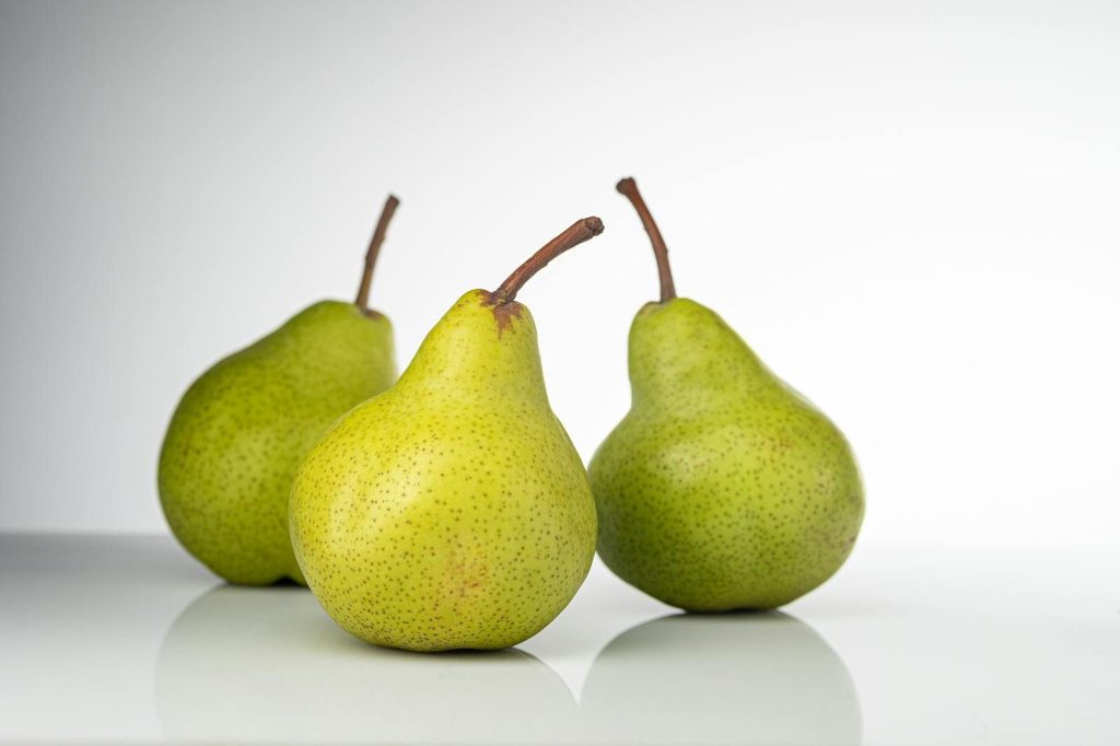 Close-up of three ripe pears on a glossy surface, ideal for healthy eating themes.