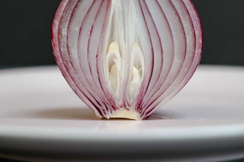 High-quality close-up image of a sliced red onion on a plate.