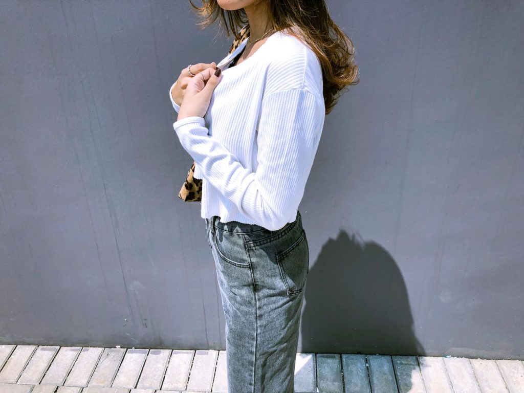 Fashionable woman posing outdoors in casual attire, emphasizing modern style.