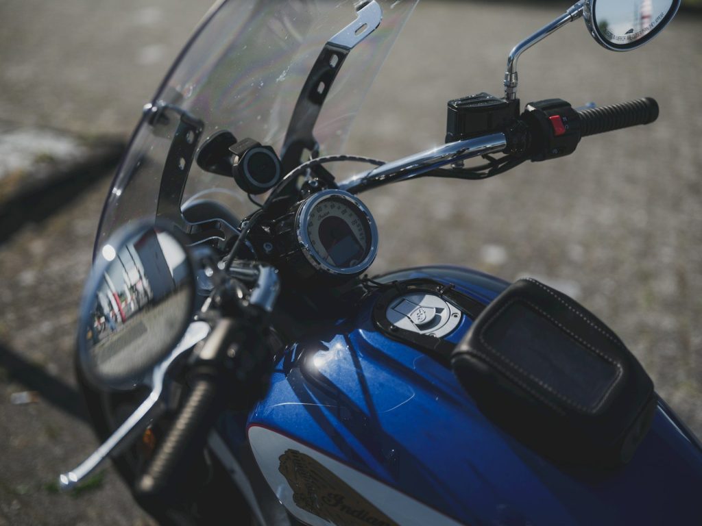 A blue motorcycle's handlebars and windshield are shown.