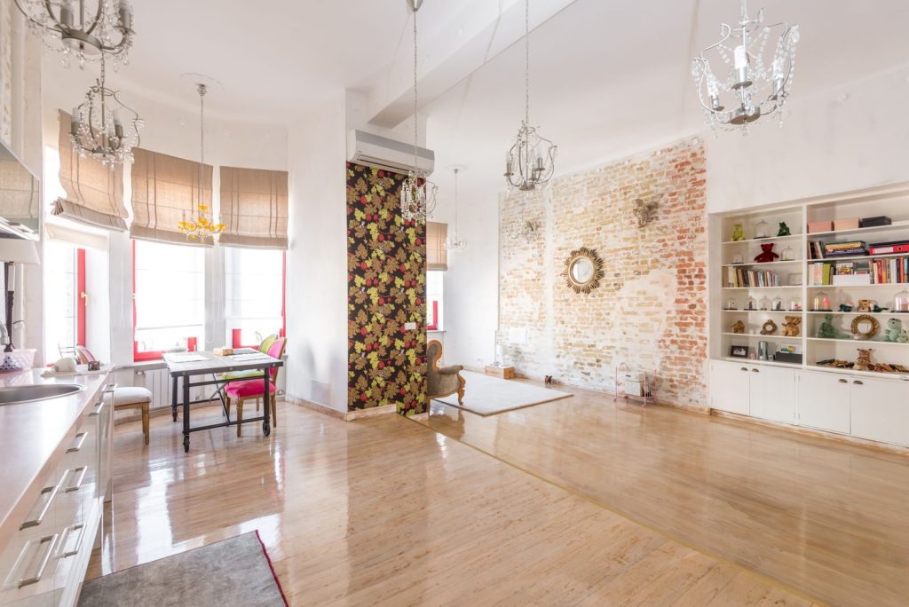 Bright modern living room featuring exposed brick detailing, elegant chandeliers, and cozy dining area.