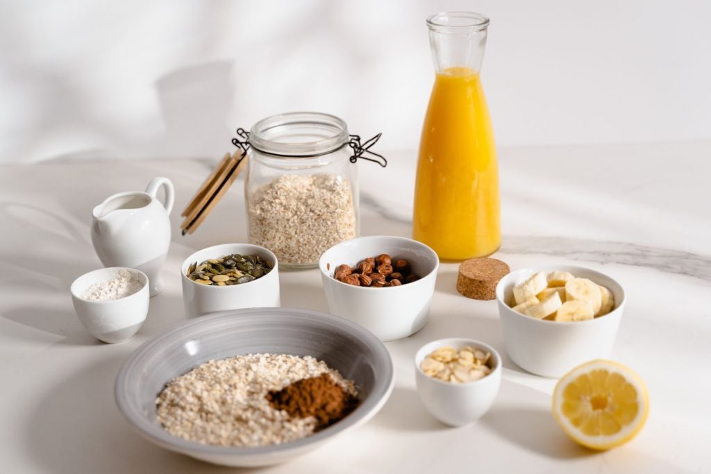 Delicious breakfast ingredients featuring oats, nuts, and fresh orange juice on a bright surface.