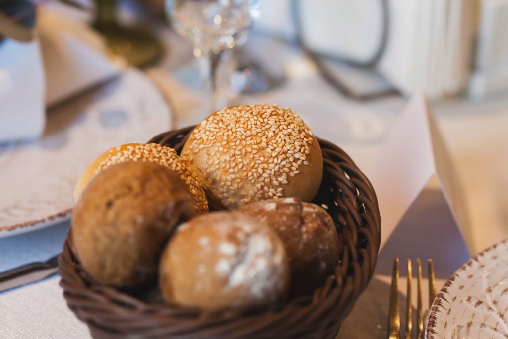 Close-up of assorted bread rolls with sesame seeds in a restaurant setting.
