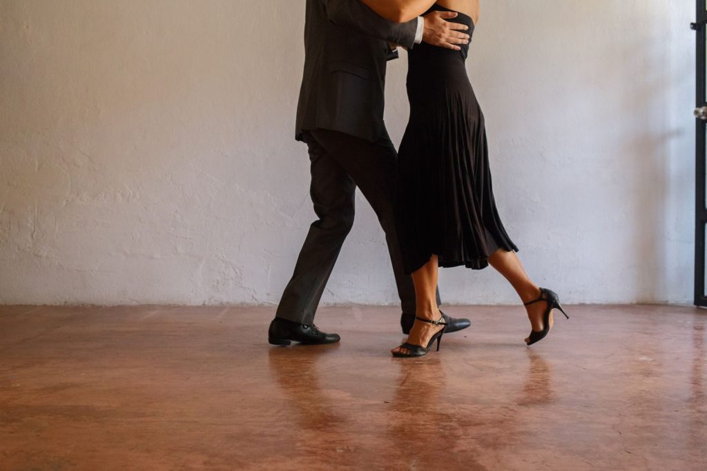 Elegant couple performing tango dance on concrete floor, showcasing grace and poise.
