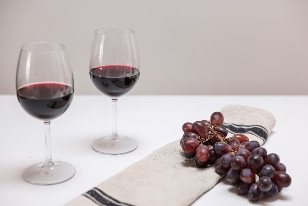 Minimalist still life photo with red wine and grapes on a napkin.