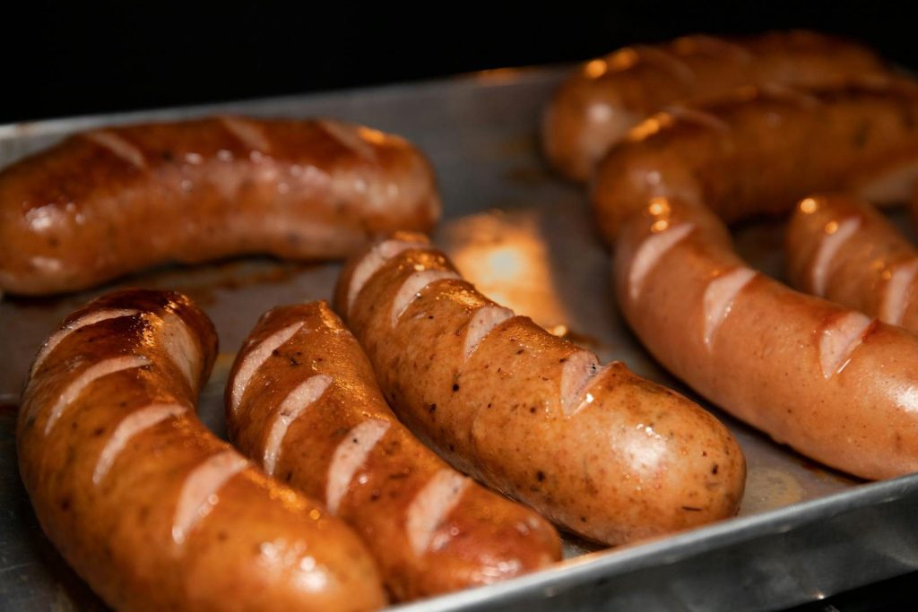 A close-up of juicy grilled sausages on a metal tray, perfect for food lovers.