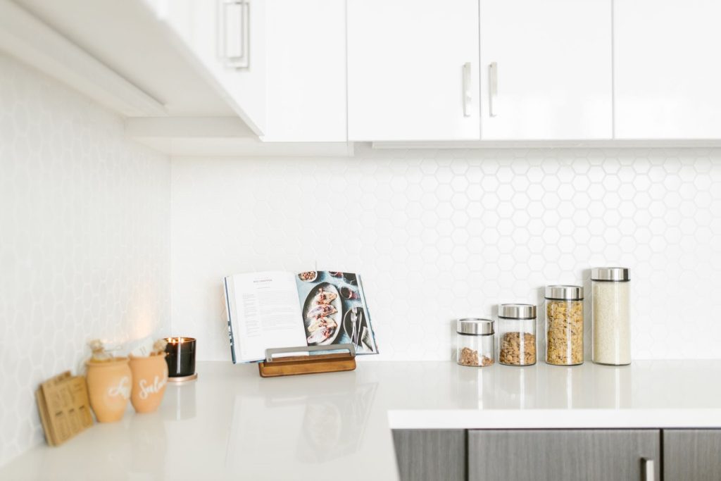 Bright minimalist kitchen interior showcasing decor and storage jars on a sleek countertop.