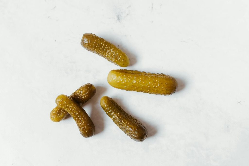 Five pickled cucumbers arranged on a clean white background, emphasizing texture and color.