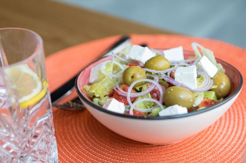 A vibrant Mediterranean salad with feta, olives, and fresh vegetables served in a white bowl.