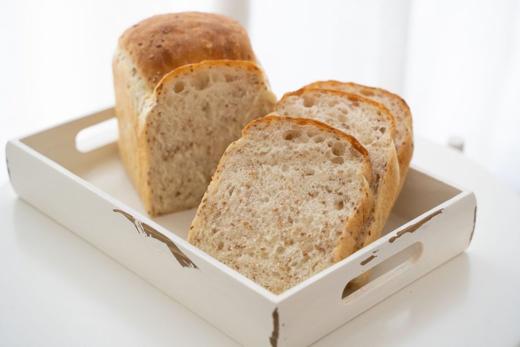 Close-up of freshly sliced homemade bread on a rustic white tray, perfect for breakfast.