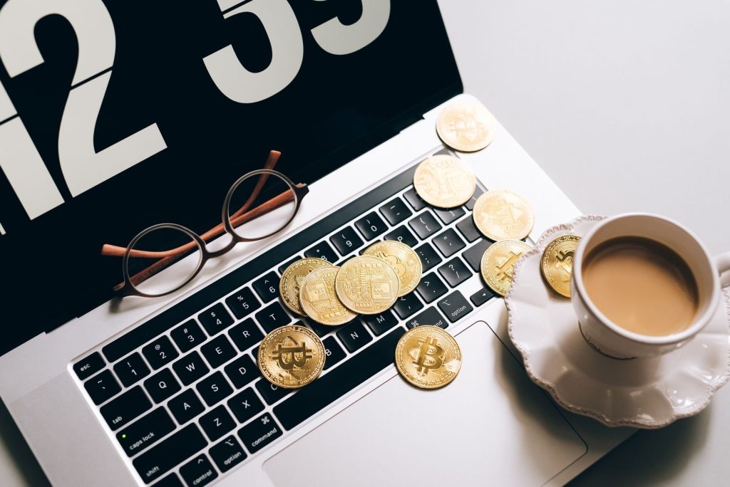 Laptop keyboard covered with Bitcoin coins and a coffee cup nearby, symbolizing cryptocurrency and work balance.