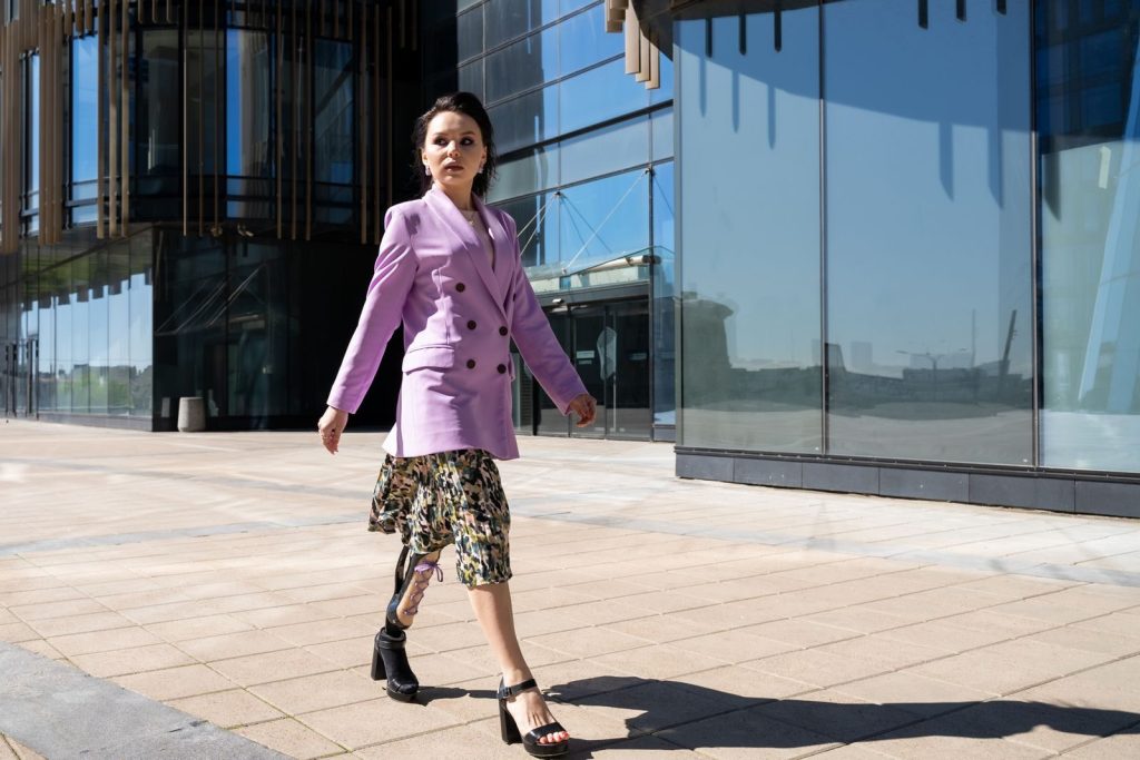 Stylish woman with prosthetic leg striding in urban setting, showcasing elegance and empowerment.